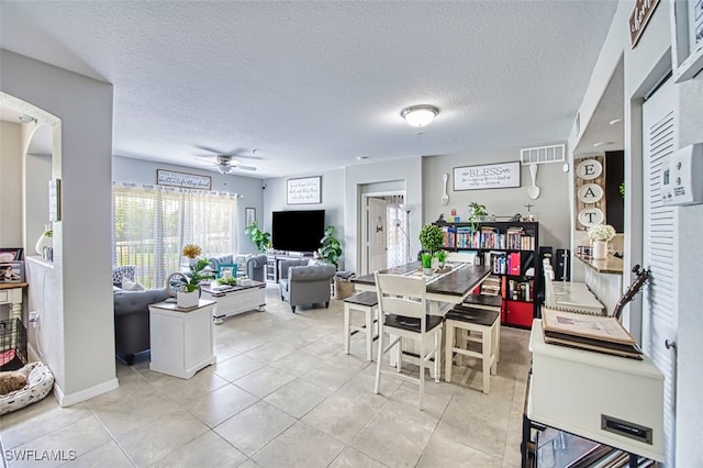 13160 Bella Casa Cir Unit 2115, Fort Myers, FL 33966 - dining room with ceiling fan, a textured ceiling, arched walkways, and light tile patterned flooring