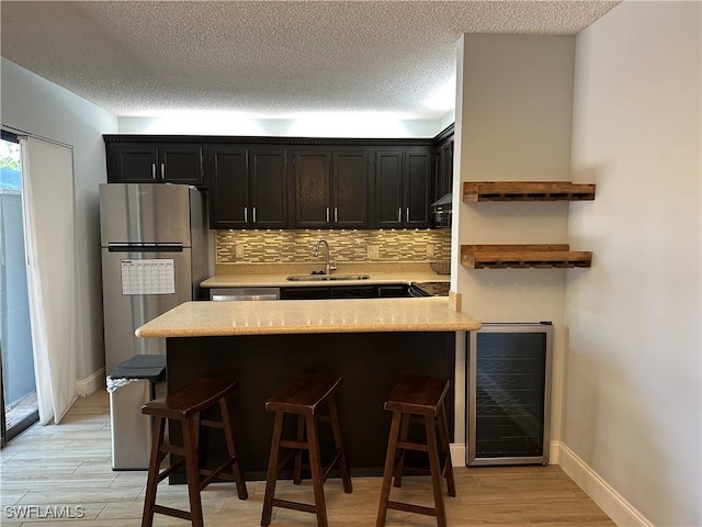 5226 Cedarbend Dr Unit 2, Fort Myers, FL 33919 - kitchen with wine cooler, a sink, light countertops, a kitchen breakfast bar, and decorative backsplash