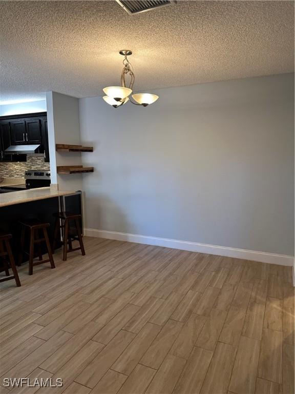 5226 Cedarbend Dr Unit 2, Fort Myers, FL 33919 - dining room with light wood-style flooring, a textured ceiling, baseboards, and a chandelier