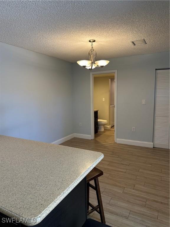 5226 Cedarbend Dr Unit 2, Fort Myers, FL 33919 - unfurnished dining area with a chandelier, baseboards, light wood-type flooring, and a textured ceiling