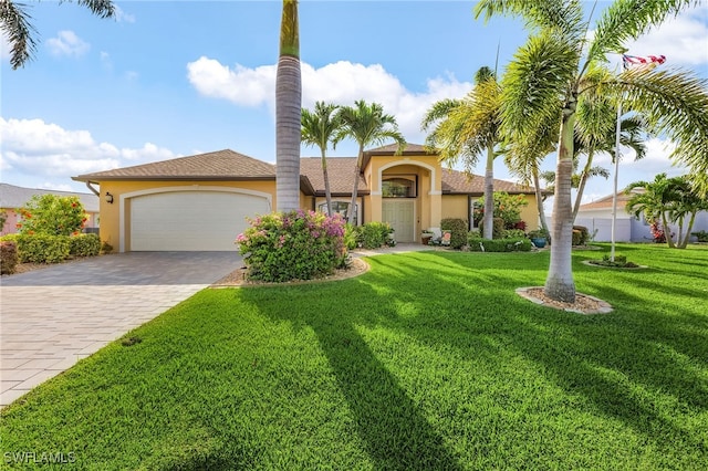 1311 SE 10th Pl, Cape Coral, FL 33990 - mediterranean / spanish home with stucco siding, an attached garage, a front yard, and decorative driveway