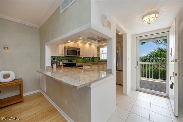 21 High Point Cir E Unit 502, Naples, FL 34103 - kitchen with appliances with stainless steel finishes, ornamental molding, a peninsula, light stone countertops, and decorative backsplash