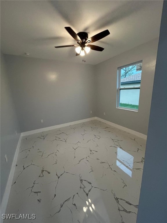 spare room featuring baseboards, a ceiling fan, and marble finish floors