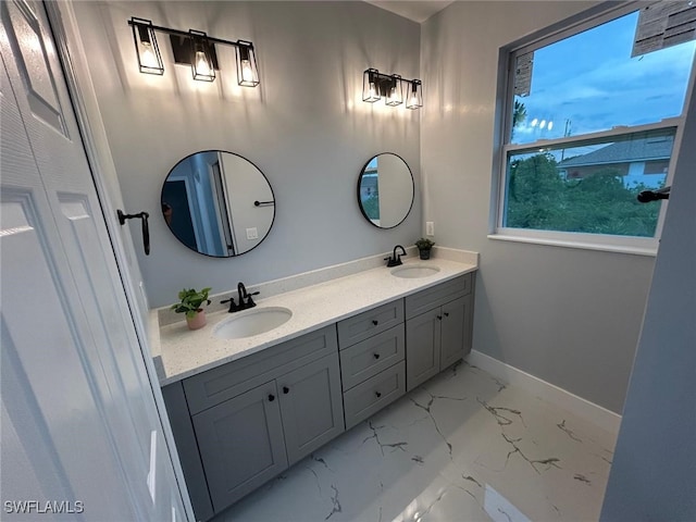 bathroom with double vanity, marble look tile flooring, and baseboards