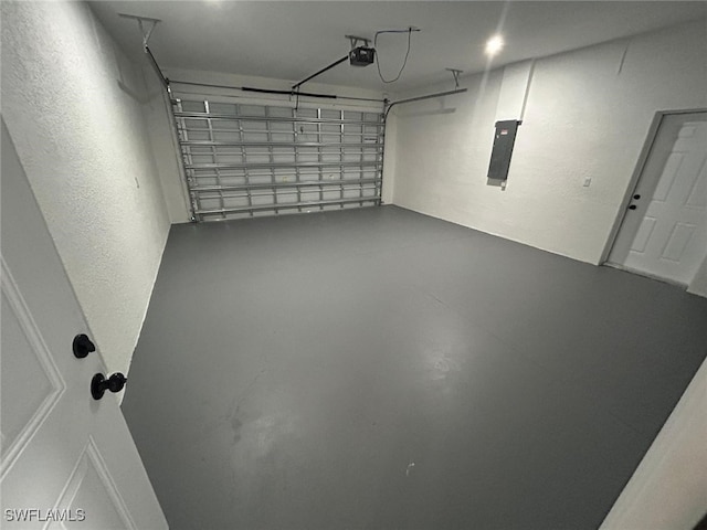 garage featuring a garage door opener, electric panel, and a textured wall