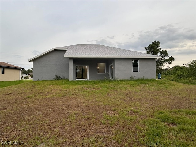 back of property featuring a yard and stucco siding