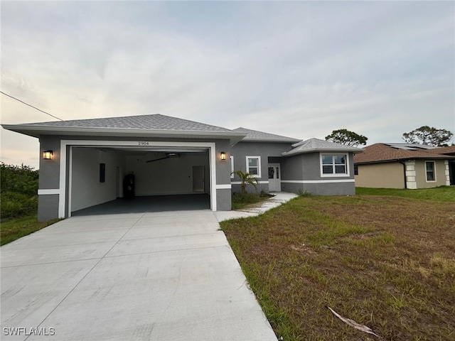 prairie-style house featuring an attached garage, driveway, stucco siding, and a front yard