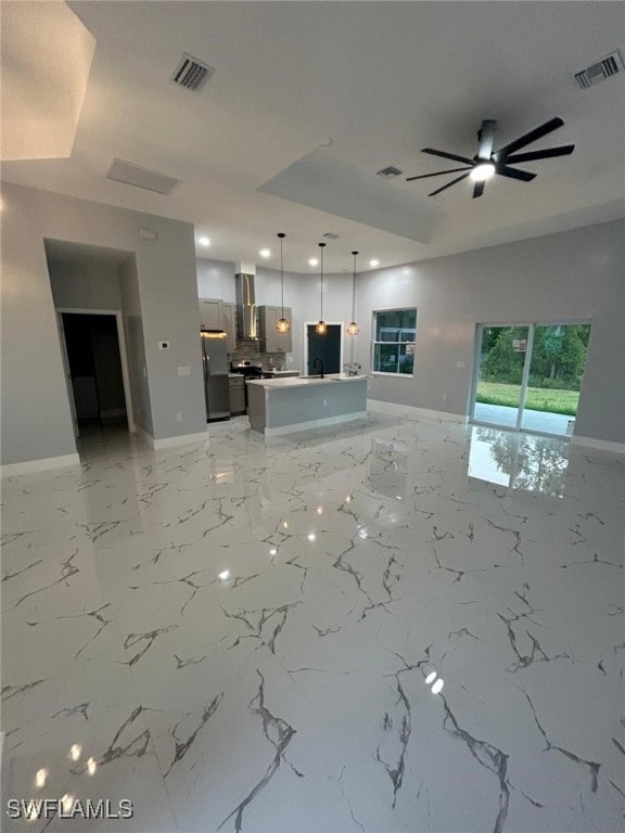 unfurnished living room featuring baseboards, a ceiling fan, recessed lighting, a sink, and light marble finish floors