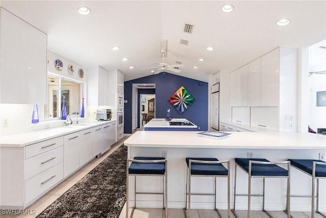 12439 Prather Ave, Port Charlotte, FL 33981 - kitchen with modern cabinets, white cabinets, a kitchen breakfast bar, vaulted ceiling, and recessed lighting