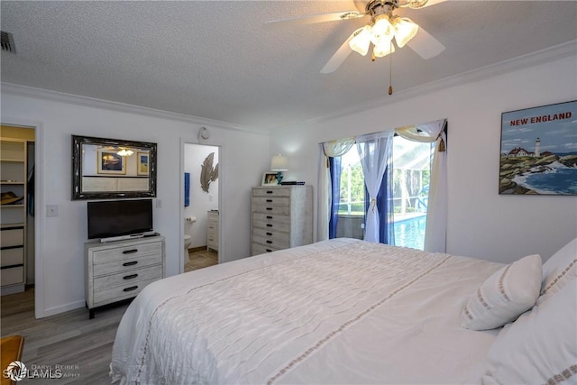 1303 Thompson St, North Fort Myers, FL 33903 - bedroom featuring crown molding, a walk in closet, wood finished floors, a textured ceiling, and ensuite bathroom