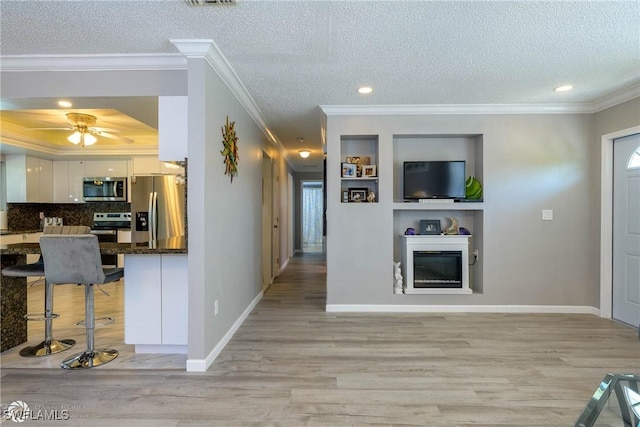 1303 Thompson St, North Fort Myers, FL 33903 - living room with light wood-type flooring, crown molding, a textured ceiling, ceiling fan, and a glass covered fireplace
