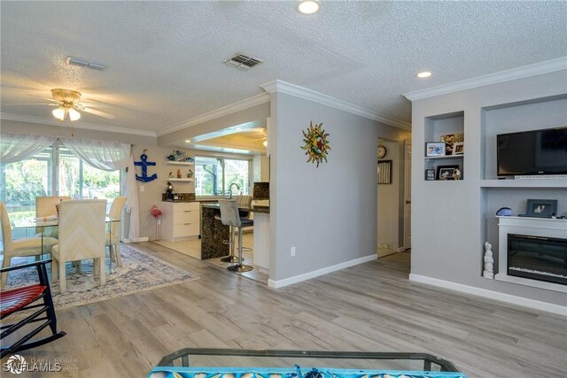 1303 Thompson St, North Fort Myers, FL 33903 - living area with a textured ceiling, light wood finished floors, a ceiling fan, baseboards, and crown molding