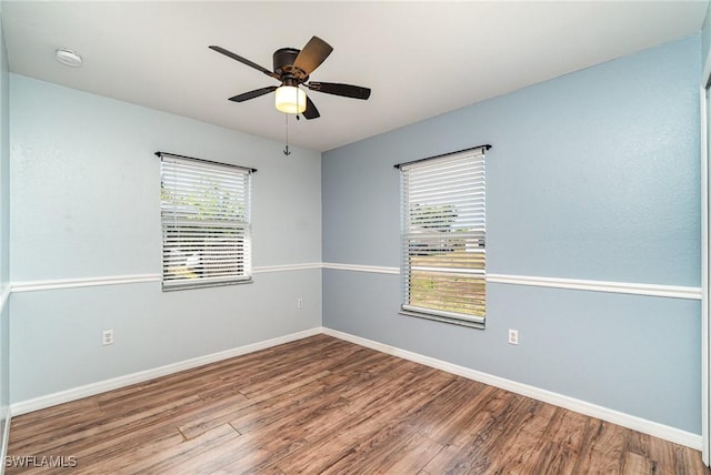empty room featuring wood finished floors, baseboards, a ceiling fan, and a smoke detector