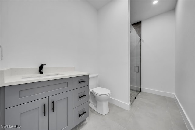 bathroom with toilet, vanity, a shower stall, and baseboards