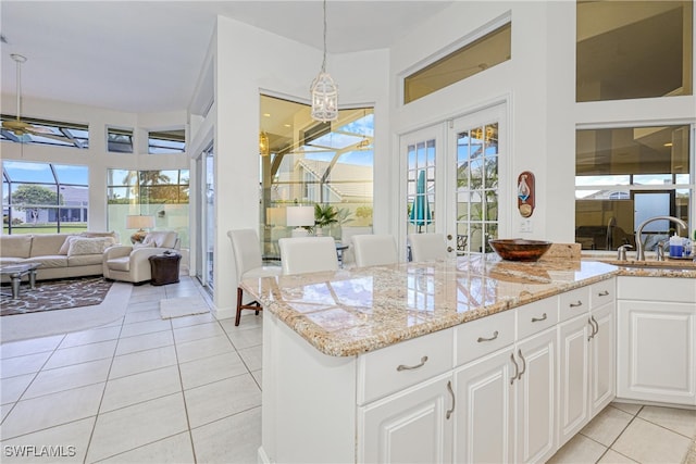 28839 Winthrop Cir, Bonita Springs, FL 34134 - kitchen featuring light tile patterned flooring, a sink, light stone countertops, white cabinets, and hanging light fixtures