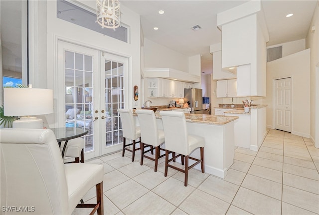 28839 Winthrop Cir, Bonita Springs, FL 34134 - kitchen with french doors, a peninsula, light tile patterned flooring, white cabinets, and recessed lighting