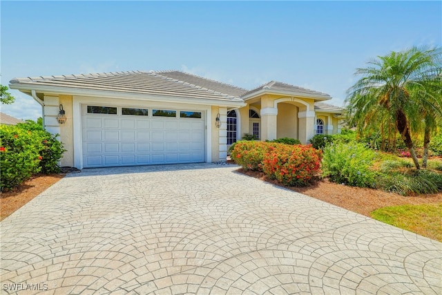 28839 Winthrop Cir, Bonita Springs, FL 34134 - ranch-style home with stucco siding, an attached garage, decorative driveway, and a tiled roof