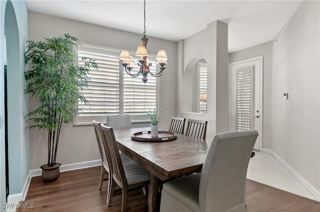 3045 Driftwood Way Unit 3707, Naples, FL 34109 - dining space featuring a chandelier, arched walkways, wood finished floors, and baseboards