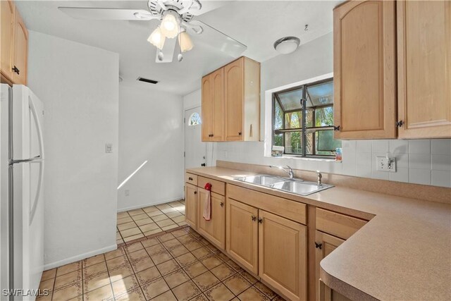 kitchen featuring freestanding refrigerator, light brown cabinets, a sink, and light countertops