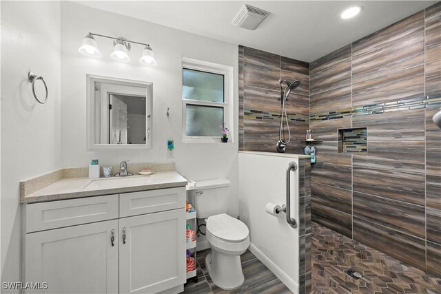 bathroom featuring a walk in shower, toilet, vanity, and wood finished floors