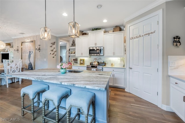 28268 Seasons Tide Ave, Bonita Springs, FL 34135 - kitchen featuring appliances with stainless steel finishes, a kitchen breakfast bar, ornamental molding, white cabinetry, and wood finished floors