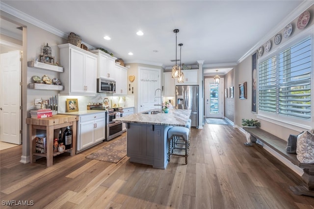 28268 Seasons Tide Ave, Bonita Springs, FL 34135 - kitchen featuring stainless steel appliances, ornamental molding, white cabinetry, open shelves, and a kitchen bar