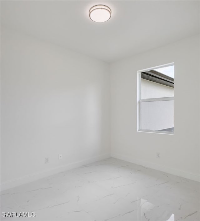 unfurnished room with marble look tiles and baseboards