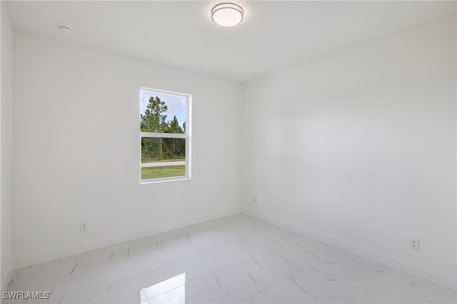 unfurnished room with marble look tiles and baseboards