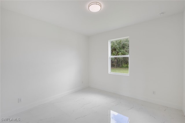 unfurnished room with light marble finish flooring and baseboards
