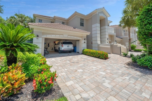mediterranean / spanish-style house with stucco siding, decorative driveway, a tiled roof, and an attached garage