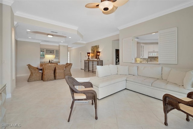 living area with crown molding, light tile patterned floors, a raised ceiling, ceiling fan, and bar area