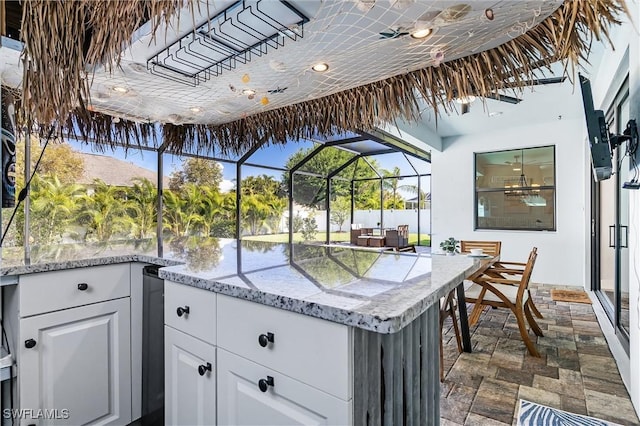 view of patio featuring an outdoor kitchen, glass enclosure, and a bar