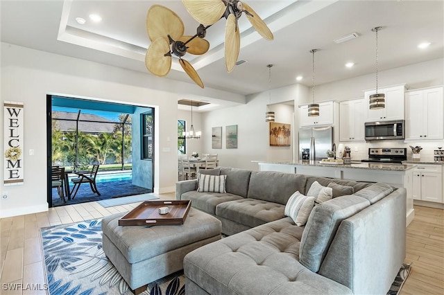 living room with light wood finished floors, a ceiling fan, baseboards, and recessed lighting