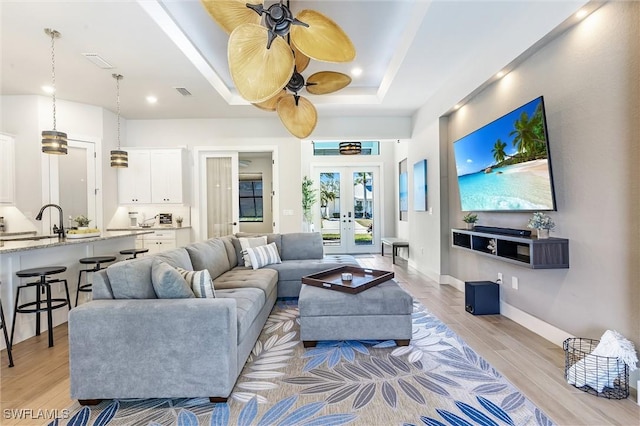 living room featuring light wood finished floors, french doors, baseboards, and recessed lighting