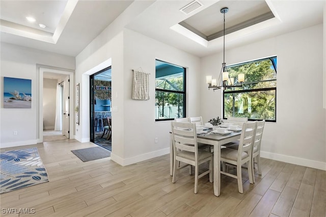 dining area with a tray ceiling, light wood-type flooring, and baseboards