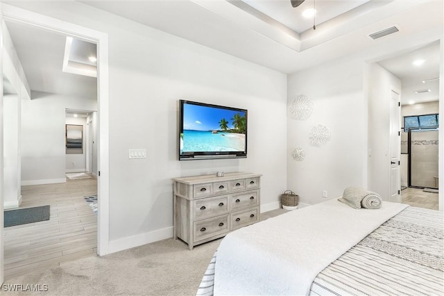 bedroom with baseboards, a tray ceiling, and connected bathroom