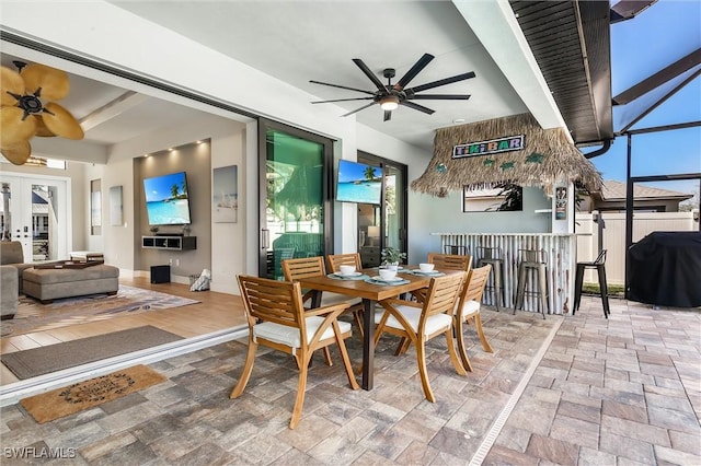dining room featuring a ceiling fan, stone finish floors, and french doors