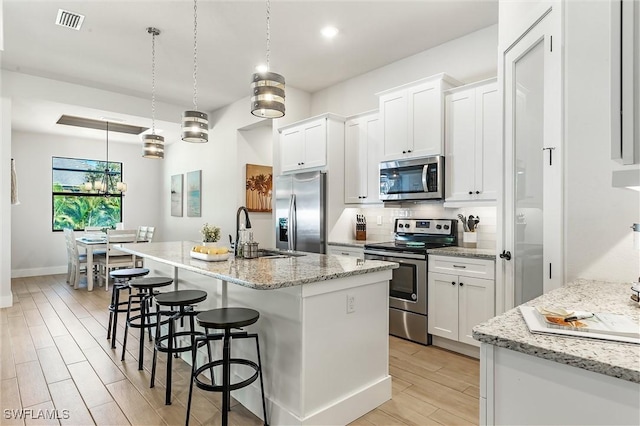 kitchen featuring stainless steel appliances, a sink, light wood-style floors, white cabinetry, and recessed lighting