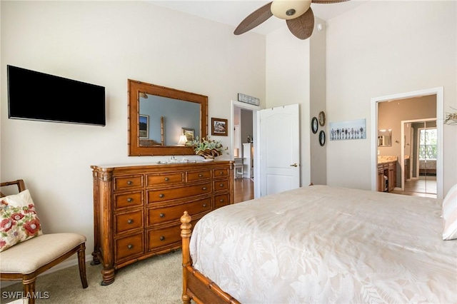 bedroom featuring high vaulted ceiling, light colored carpet, connected bathroom, and a ceiling fan