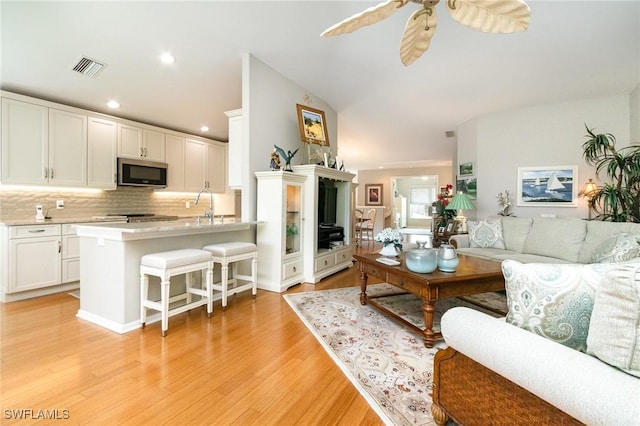 living area featuring light wood-type flooring, a ceiling fan, and recessed lighting