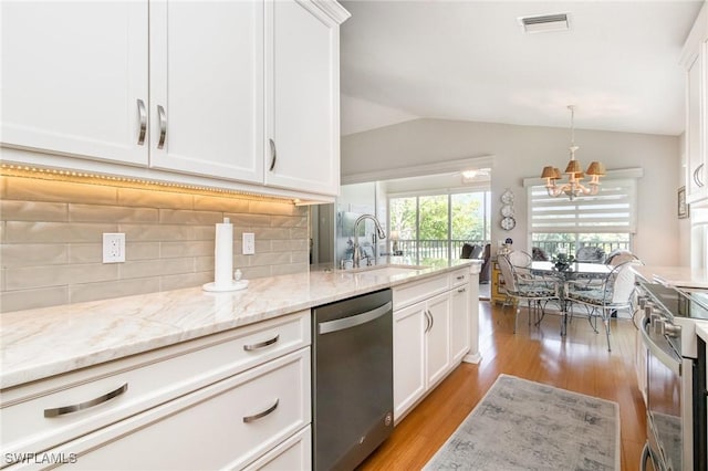 kitchen featuring appliances with stainless steel finishes, a sink, a chandelier, lofted ceiling, and white cabinetry