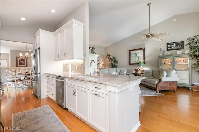 kitchen featuring stainless steel appliances, a sink, white cabinets, light wood-type flooring, and a chandelier