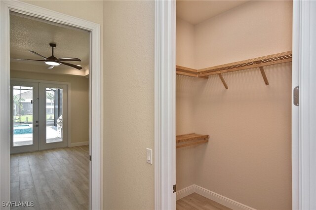 walk in closet featuring light wood-style floors, french doors, and a ceiling fan