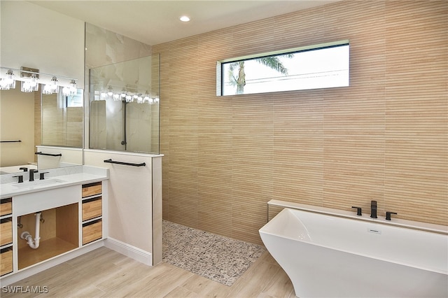 full bath featuring a walk in shower, a freestanding bath, vanity, wood finished floors, and recessed lighting