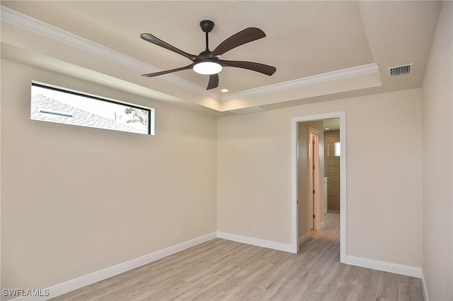 unfurnished room with a tray ceiling, crown molding, light wood finished floors, ceiling fan, and baseboards