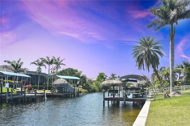 dock with boat lift, fence, and a water view