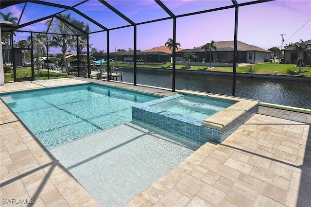 pool at dusk featuring a patio, a water view, a lanai, and a pool with connected hot tub