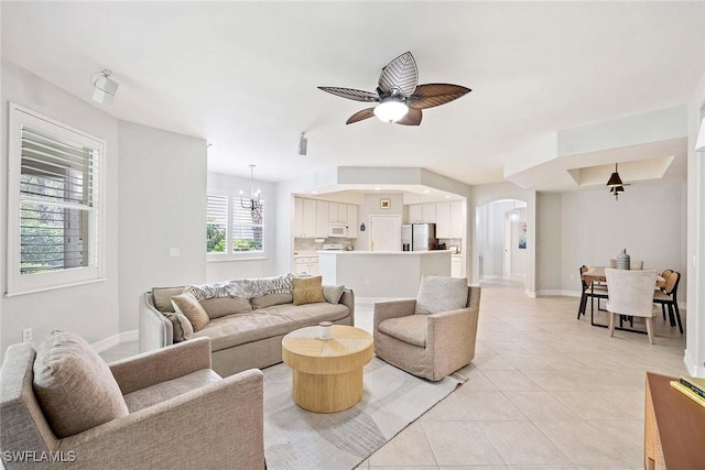 1786 Tarpon Bay Dr S Unit 102, Naples, FL 34119 - living room featuring arched walkways, light tile patterned flooring, ceiling fan, and baseboards