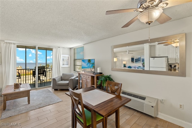 5900 Bonita Beach Rd # 1405, Bonita Springs, FL 34134 - dining space with a textured ceiling, light wood-style floors, ceiling fan, baseboards, and a wall mounted air conditioner