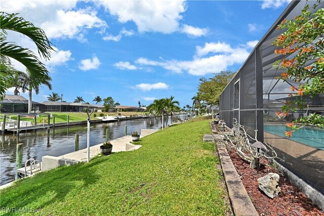 view of grassy yard with a water view, glass enclosure, and an outdoor pool